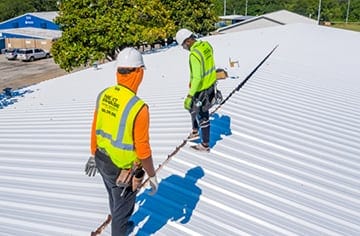 Roofing contractor inspecting metal commercial roof