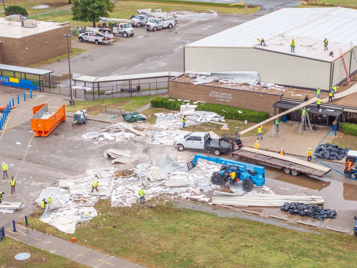 Workers cleaning up debris and implementing roof repairs on Newcastle Elementary.