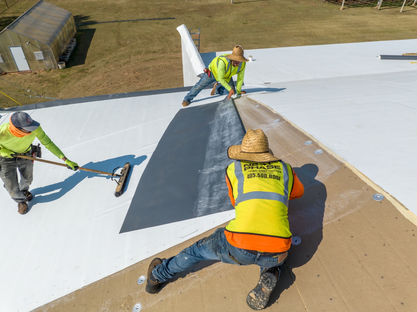 Workers putting TPO down on a flat roof.