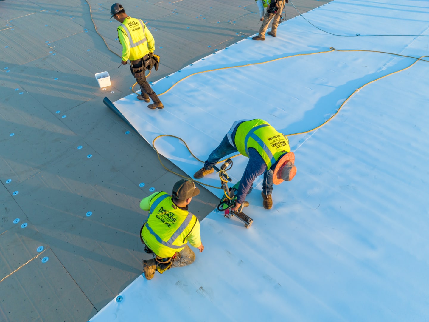 Workers putting TPO down on a flat roof.