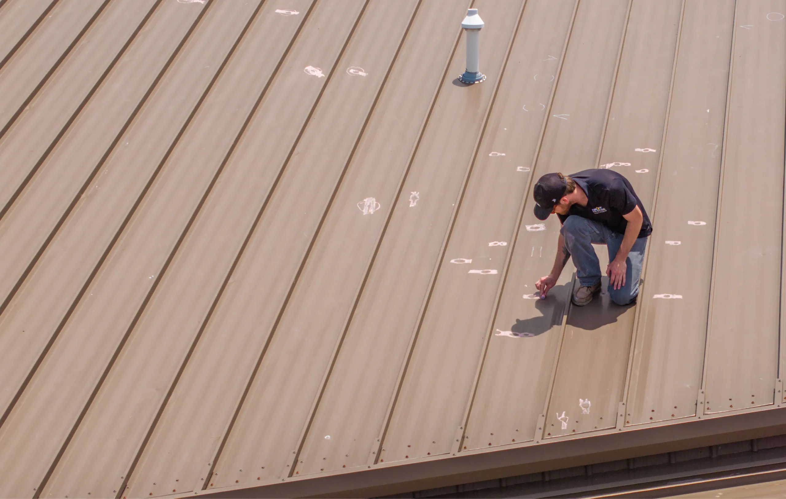 Crew marking hail damage on metal roof with chalk