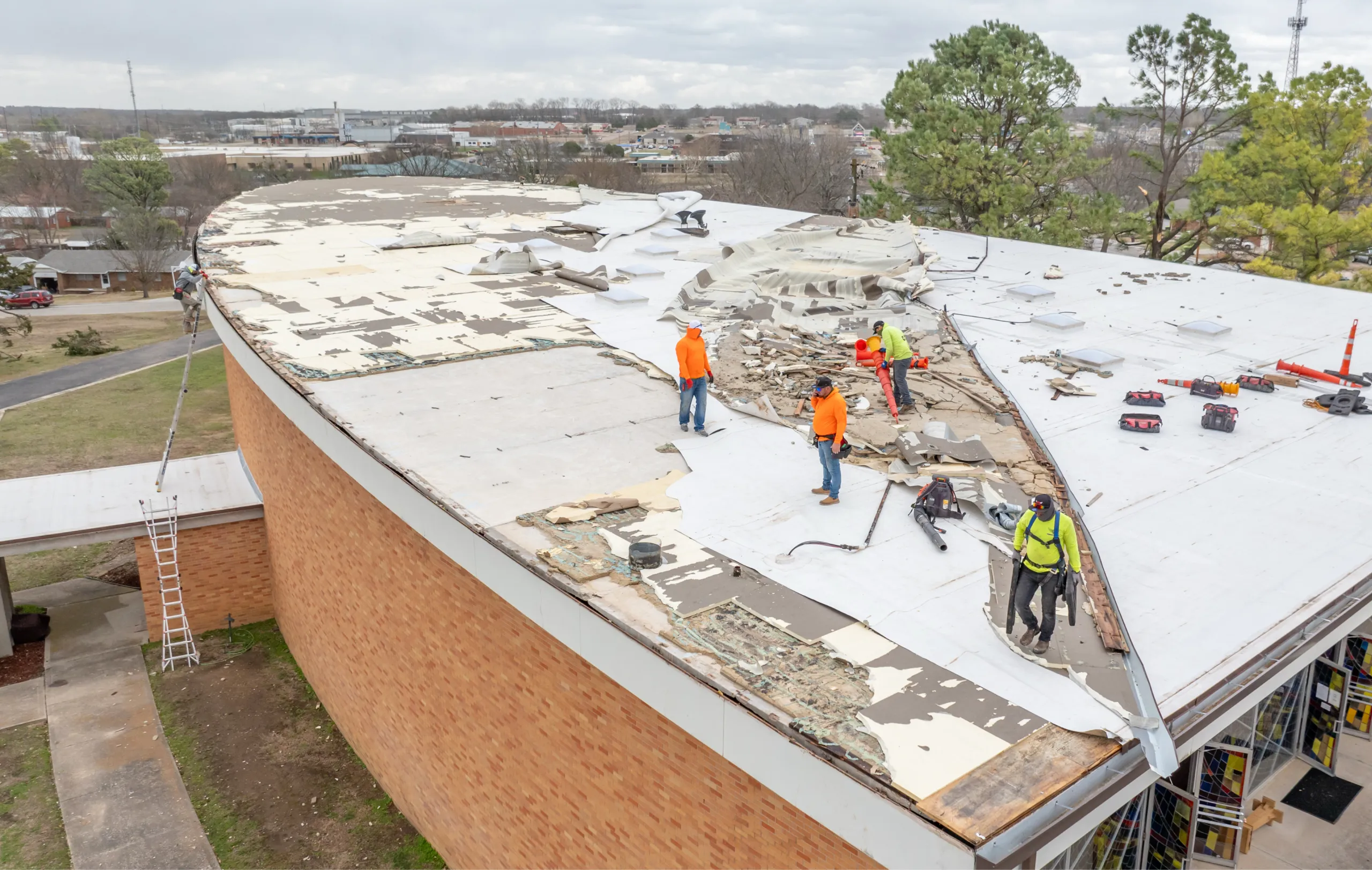 Storm damage cleanup crew after storm ripped off a TPO roof from commercial building