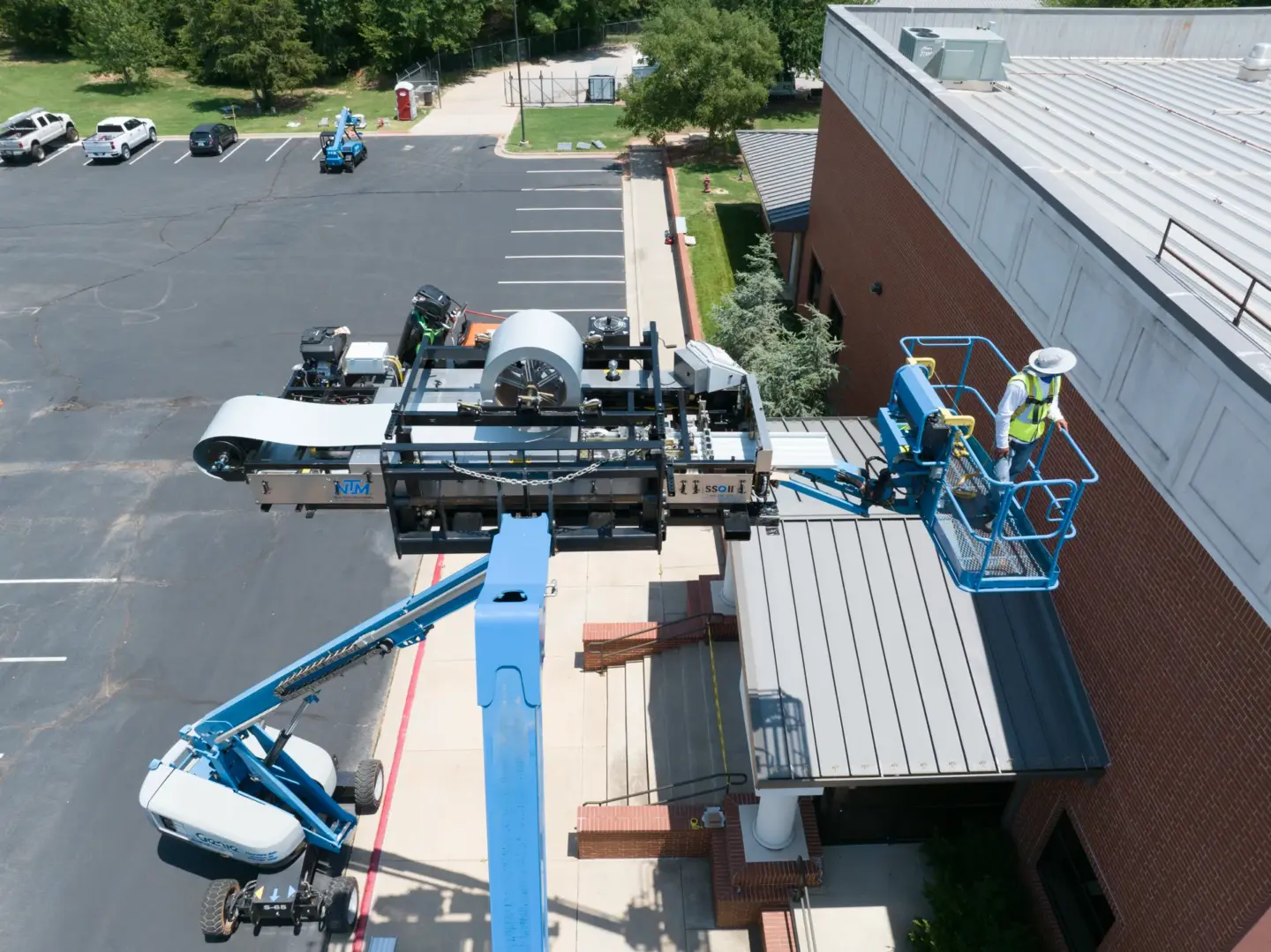 Workers forming standing seam metal panels with a roller