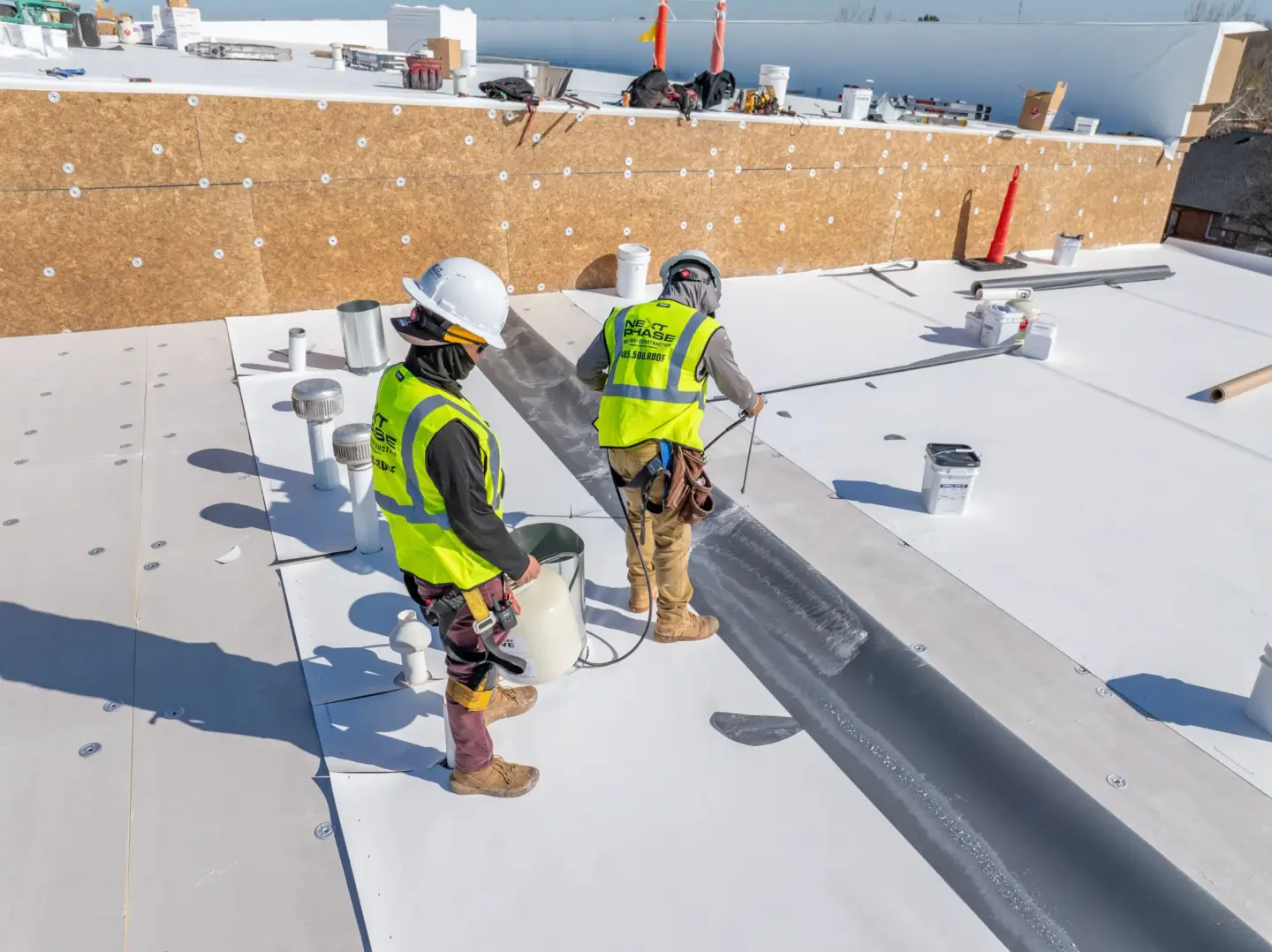 Workers spraying down TPO on a flat roof