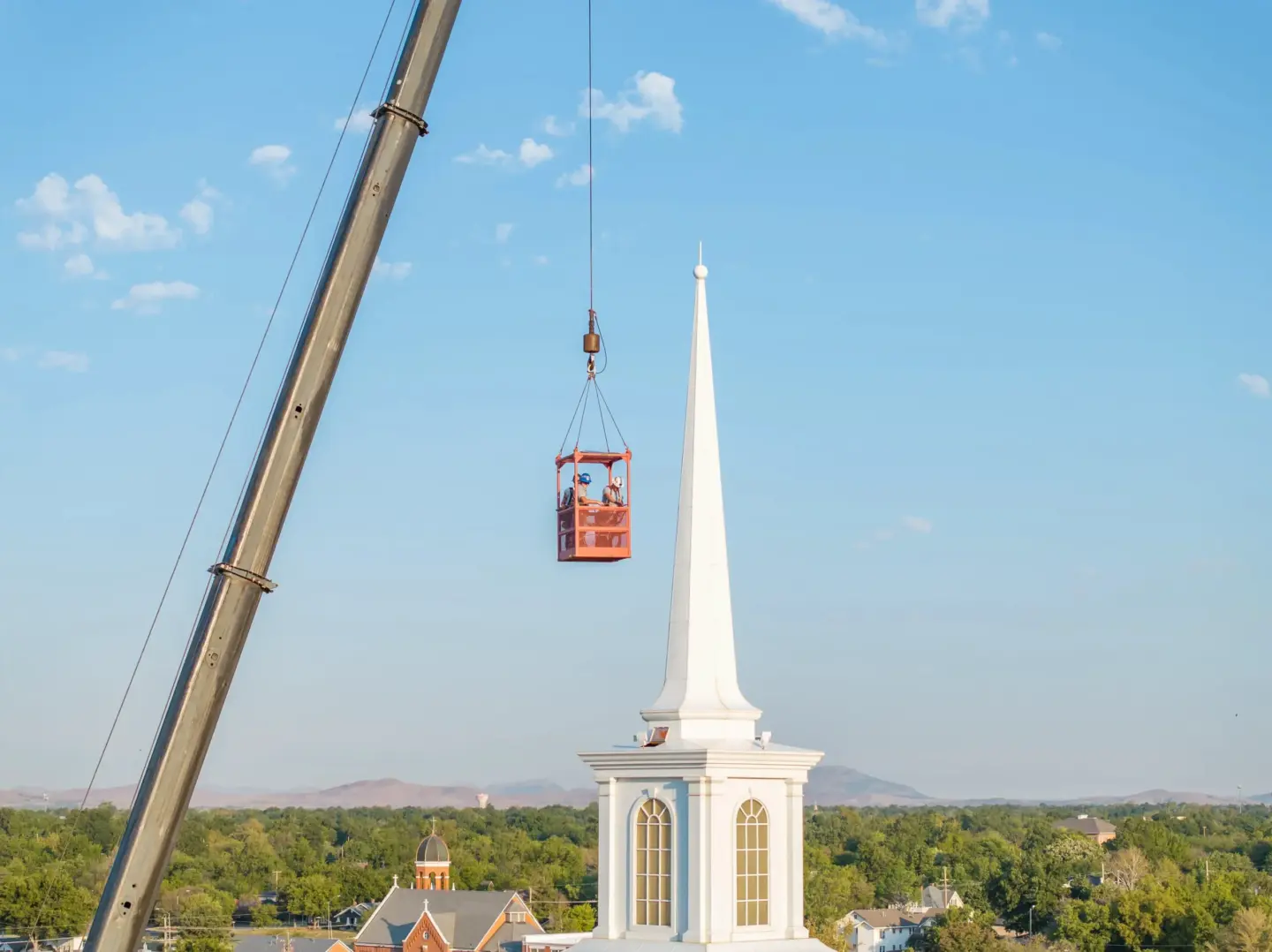 Workers in a crane repairing a steeple