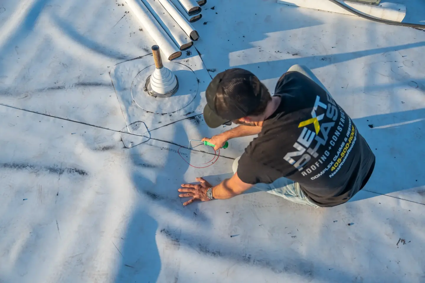 Worker inspecting TPO on a flat roof